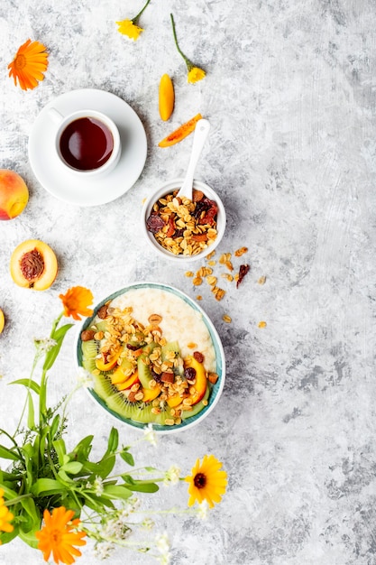 Ciotola di porridge di farina d'avena fresca con kiwi, pesca e muesli per colazione