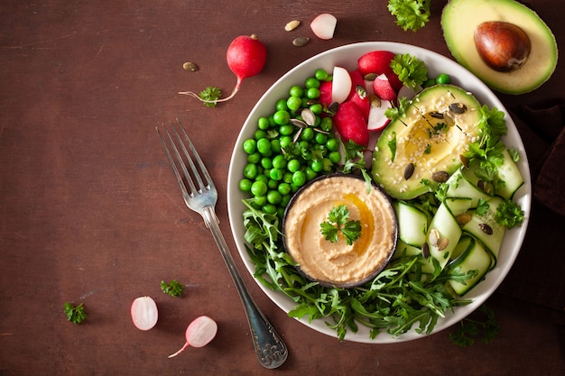 Ciotola di pranzo vegana sana con il ravanello del hummus dei piselli del cetriolo dell'avocaco