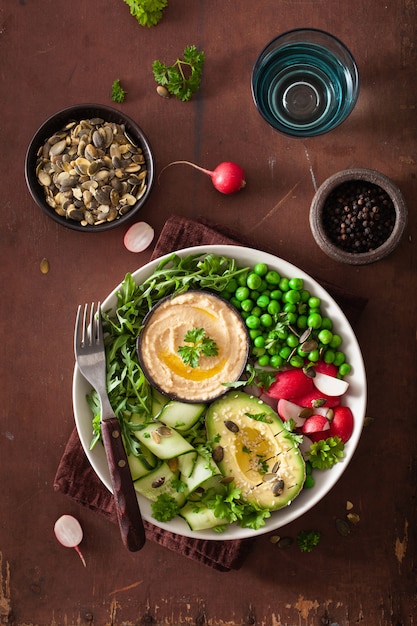 Ciotola di pranzo vegana sana con il ravanello del hummus dei piselli del cetriolo dell'avocaco