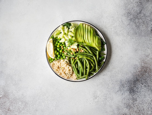 Ciotola di quinoa con fagiolini, piselli, cetrioli, avocado e pinoli su un grigio