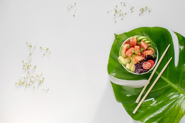 Ciotola di salmone hawaiano con cetrioli, pomodori, semi di sesamo, avocado.