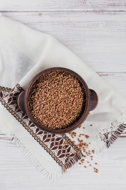 Ciotola di semole di grano saraceno crudo secco su un legno bianco. Cucinare il concetto di porridge di grano saraceno.