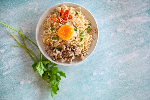 Ciotola di tagliatelle con uovo sodo carne di maiale tritata vegetale cipollotto limone sul tavolo cibo spaghetti istantanei cottura gustoso mangiare con ciotola zuppa di noodle