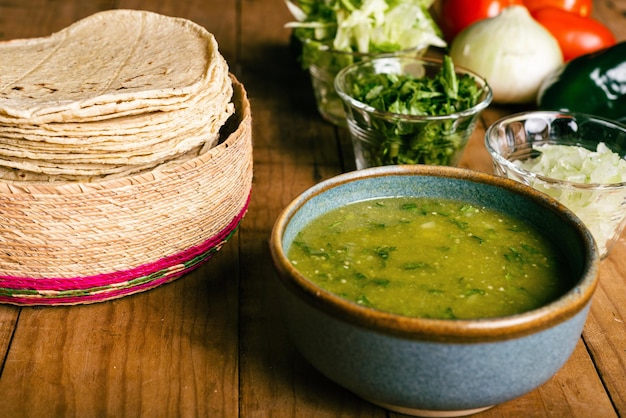 Ciotola di tortillas con salsa verde e verdure su un tavolo di legno Cibo tipico messicano