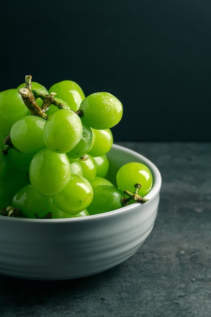 Ciotola di uva verde isolata su sfondo nero con spazio per la copia Vista ravvicinata Riprese al buio Luogo per la scrittura