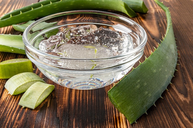 Ciotola di vetro con gel naturale di aloe vera per la cura della giovane pelle grassa problematica del viso e del corpo cosmetici biologici fondo in legno