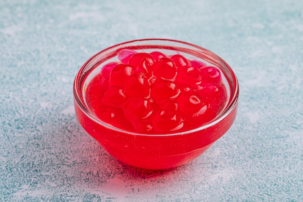 Ciotola di vetro di bollicine di perle di tapioca rosse su sfondo blu