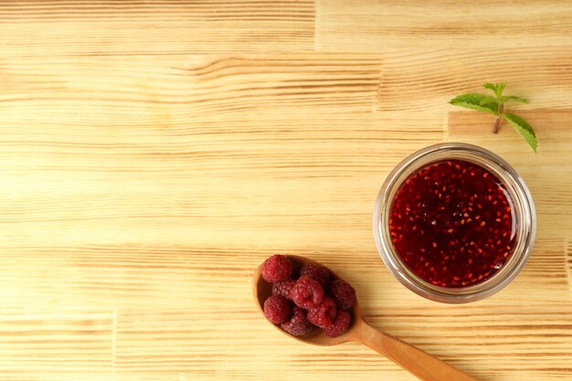 Ciotola di vetro di marmellata di lamponi con ingredienti su fondo di legno