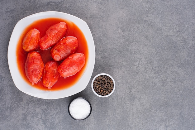 Ciotola di vetro di pomodoro marinato e sale sul tavolo di pietra.