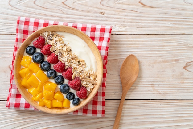 Ciotola di yogurt fatta in casa con lampone, mirtillo, mango e muesli - stile alimentare sano