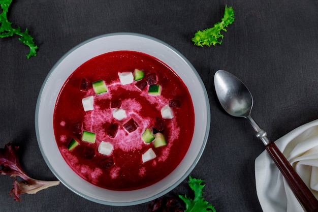 Ciotola di zuppa crema di barbabietole rosse con una radice di barbabietola fresca e foglie