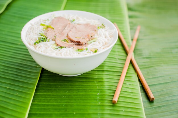 ciotola di zuppa di manzo vietnamita tradizionale Pho Bo su sfondo di foglia di banana.