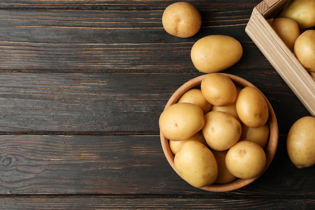 Ciotola e cestino con le giovani patate su superficie di legno