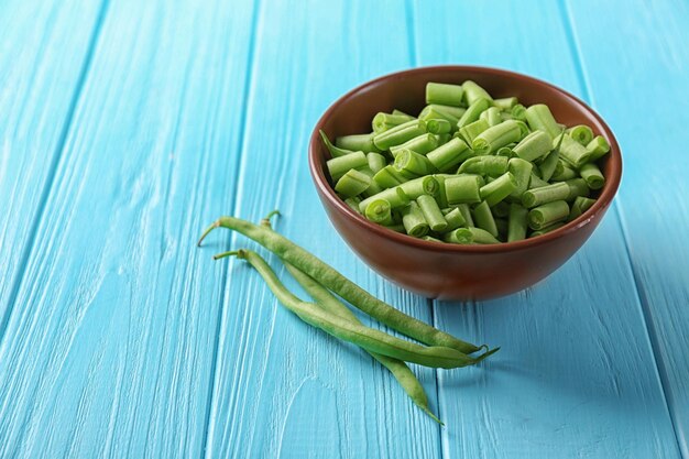 Ciotola e fagioli verdi freschi su sfondo di legno