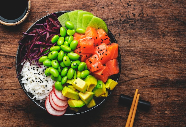 Ciotola hawaiana con salmone, avocado, ravanello, fagioli edamame, cavolo rosso e riso bianco, salsa di soia, lime e sesamo