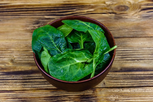 Ciotola in ceramica con foglie di spinaci su tavola di legno rustica