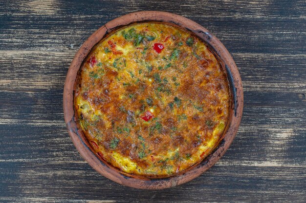 Ciotola in ceramica con frittata di verdure semplice cibo vegetariano Frittata con pomodoro, cipolla e formaggio sul tavolo di legno primo piano frittata di uova italiana vista dall'alto