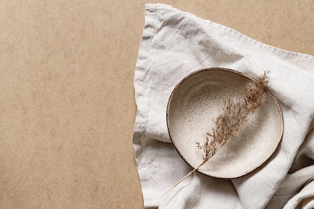 Ciotola in ceramica minimalista con pianta secca su sfondo di carta kraft Copia spazio piatto