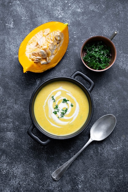 Ciotola nera con zuppa autunnale di zucca. Zuppa cremosa e deliziosa vegana con latte di cocco. Vista dall'alto. Sfondo scuro.