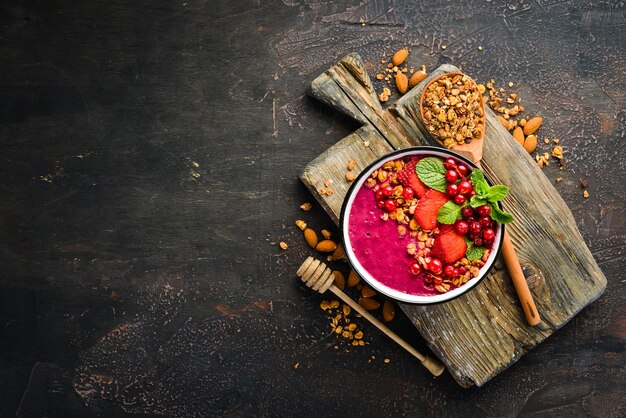 Ciotola per frullati con muesli, fragola, ribes rosso e menta Colazione Vista dall'alto Spazio libero per il testo