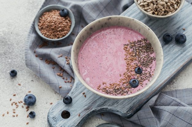 Ciotola per frullato allo yogurt rosa fatta con mirtilli freschi e semi. Concetto di cibo sano. Avvicinamento