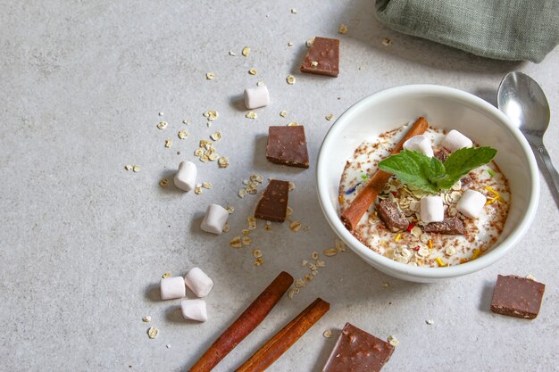 ciotola per frullato con yogurt naturale, cioccolato e cereali su sfondo grigio colazione sana