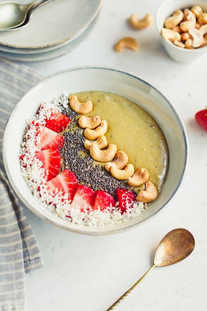 Ciotola per frullato verde con crema di cocco, banana, fragola, anacardi e semi di chia. Mangiare sano e vegano