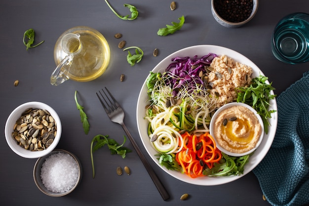 Ciotola per il couscous vegetariano con carote a spirale e zucchine, hummus e cavolo rosso