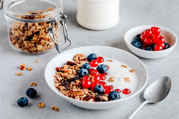 Ciotola per la colazione sana con muesli fatti in casa, mirtilli, ribes rosso e yogurt