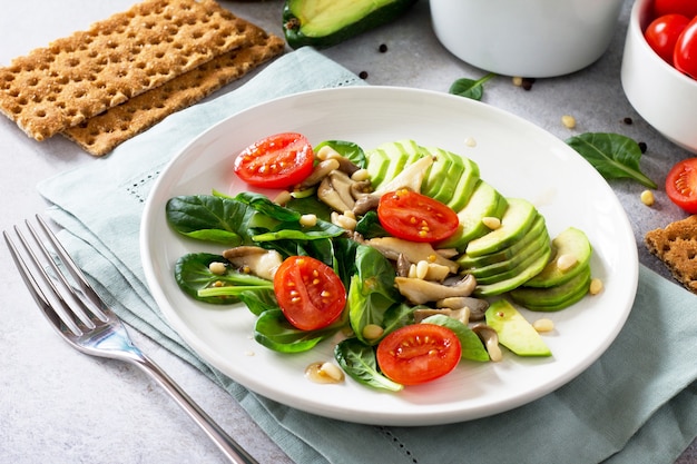 Ciotola pranzo vegetariano sano Funghi avocado pomodorini pinoli spinaci e condimento con salsa vinaigrette