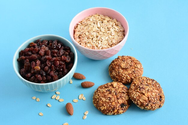 ciotole blu e rosa con uvetta e farina d'avena e biscotti d'avena sullo sfondo blu