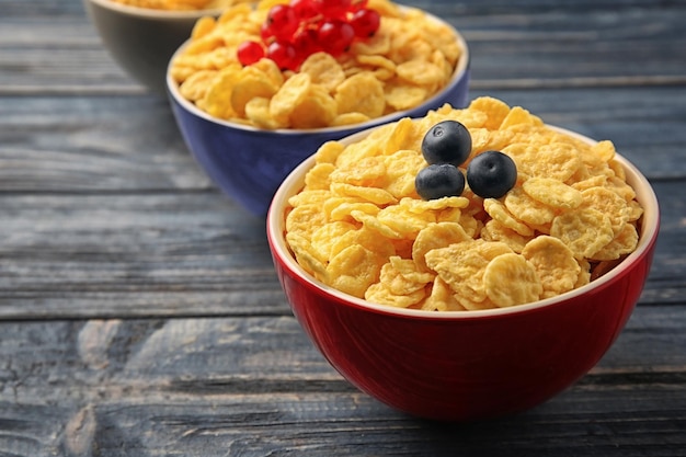 Ciotole con cornflakes e frutti di bosco sul primo piano di legno grigio del fondo