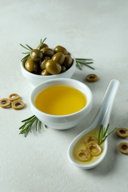 Ciotole con olive e olio su sfondo bianco con texture