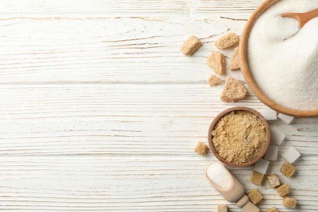 Ciotole con zucchero su fondo di legno bianco, vista superiore