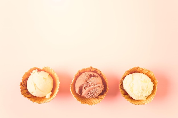 Ciotole per gelato con palline di gelato su sfondo rosa.