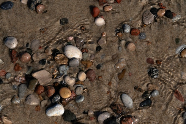 Ciottoli di mare multicolori sulla sabbia attraverso l'acqua di mare Mar Baltico Curonian Spit Regione di Kaliningrad Russia