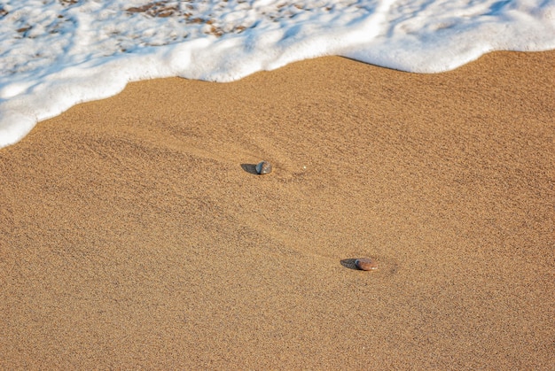 Ciottoli sabbiosi di schiuma di mare bianco su una spiaggia sabbiosa Vista sul mare calma e stimolante