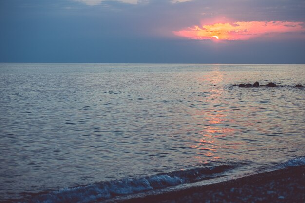 Ciottoli sulla spiaggia nella luce del tramonto. Sfondo sfocato sotto i raggi del sole al tramonto.