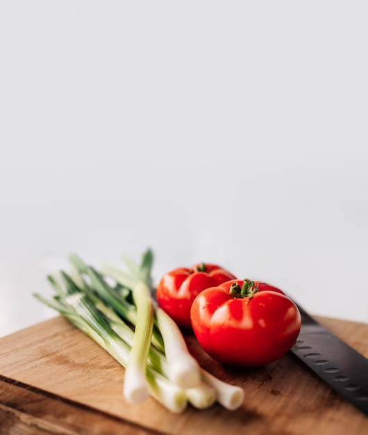 Cipolla e pomodoro freschi verdi sui precedenti di legno. Copyspace.