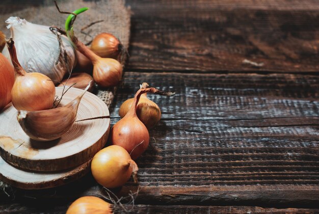 Cipolla per piantine e spicchi d'aglio su un vecchio tavolo di legno