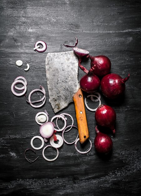 Cipolla rossa con una vecchia accetta sul rustico nero.