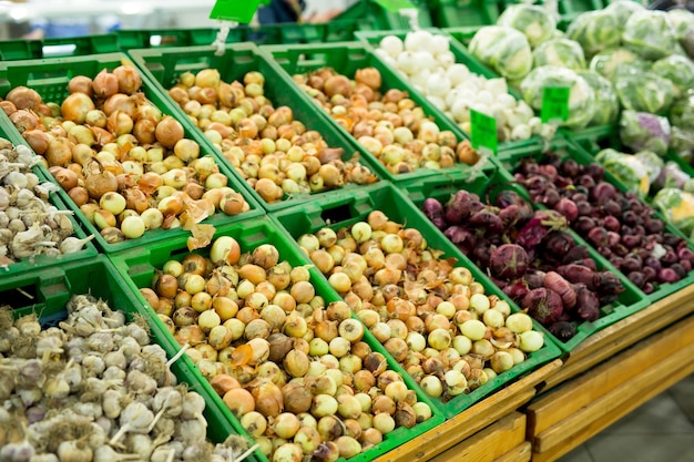 Cipolle e aglio sulla verdura dello scaffale del supermercato