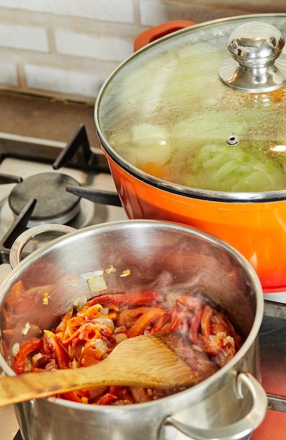 Cipolle e peperoni vengono fritti in una casseruola secondo la ricetta di Internet per cucinare