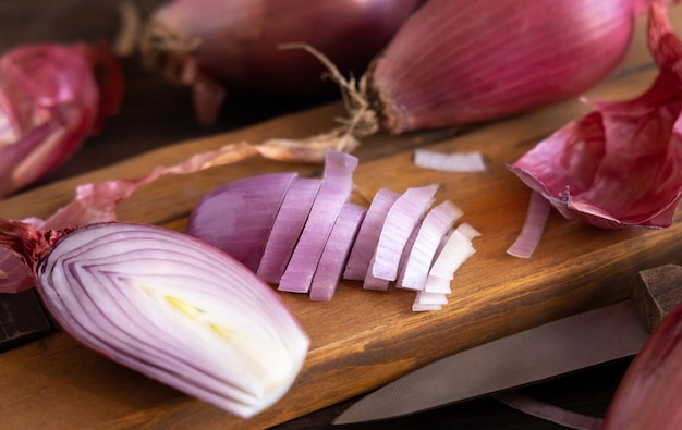 Cipolle rosse di tropea affettate con un coltello su una tavola di legno primo piano Verdura tradizionale locale del sud italiano Processo di cottura nella cucina di casa