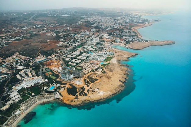 Cipro bellissima costa, mare Mediterraneo di colore turchese. Case sulla costa mediterranea. Città turistica con una lunga spiaggia. Vacanze estive al mare. vista dall'alto, vista aerea. Cipro, Ayia NAPA.