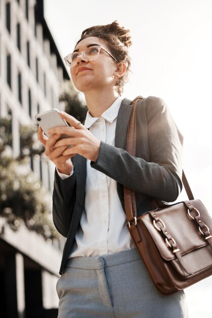 Città d'affari e donna con un cellulare che pensa e viaggia con rete di connessione internet e opportunità Persona lavoratrice in strada e consulente con un'app di navigazione per smartphone o idee