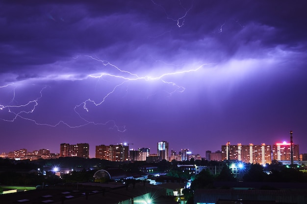 Città di notte con lampi luminosi in un cielo tempestoso