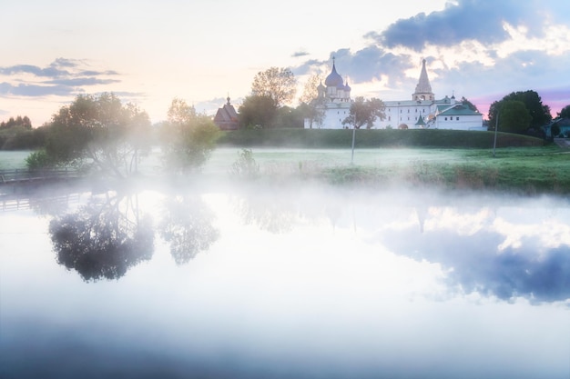 Città di Suzdal in Russia. Bellissimo paesaggio estivo all'alba nebbiosa. La cattedrale e gli alberi della Natività si riflettono nel fiume.