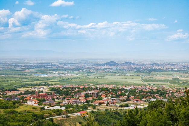 Città Plovdiv con case e campi sullo sfondo dei monti Rodopi e colline ricoperte di foreste e cielo nuvoloso