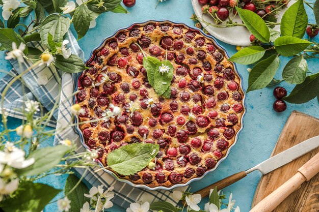 Clafoutis di ciliegie con ciliegie su sfondo blu